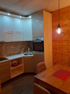 Apartman Milekic في مركونيتش غراد: مطبخ بدولاب بيضاء وطاولة خشبية