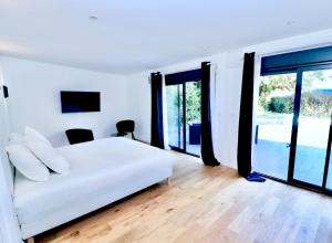 sypialnia z białym łóżkiem i dużymi oknami w obiekcie Le Domaine des Gallois w mieście Cornant