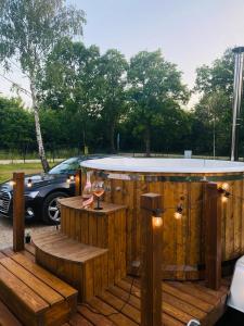 a wooden deck with a hot tub with a glass of wine at Dębowy Zakątek Sasino in Sasino
