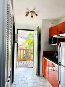 cocina con ventilador de techo y puerta a un balcón en Studio spacieux vue mer au DIAMANT avec piscine, en Le Diamant