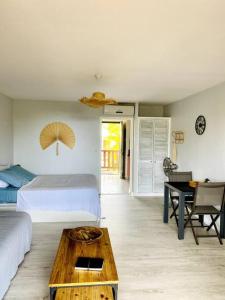 a bedroom with a bed and a table and a desk at Studio spacieux vue mer au DIAMANT avec piscine in Le Diamant