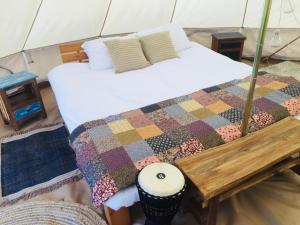 una camera con un letto con una trapunta e un tavolo di Glór na d'Tonnta Glamping a Sligo