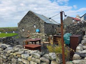 a stone house with a table and a stone wall at Glór na d'Tonnta Glamping in Sligo
