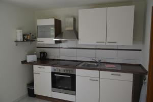 a kitchen with white cabinets and a sink at Ferienwohnung am Storchennest in Burkau in Burkau