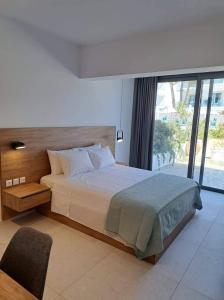 a bedroom with a large bed and a large window at Courtyard Luxury Suites “ APOSTOLOS” in Pefki