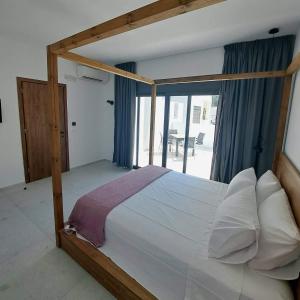 a bedroom with a wooden canopy bed with a window at Courtyard Luxury Suites “ APOSTOLOS” in Pefki