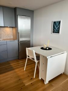 a white kitchen with a table and a refrigerator at Elme apartment in Växjö