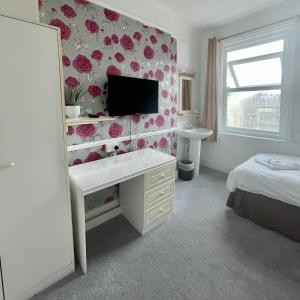 a bedroom with a desk and a tv on a wall at THE LODGE BOURNEMOUTH in Bournemouth