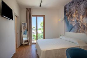 a bedroom with a bed and a tv and a balcony at LA DAMA in San Vito lo Capo