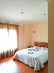 ValdosendeにあるRestaurante Vessada - Alojamento Localのベッドルーム1室(白い掛け布団、窓付)