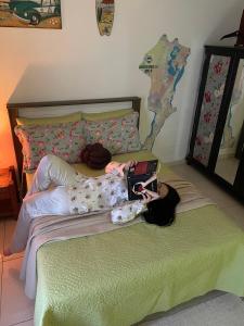 una mujer acostada en una cama con un portátil en Gara Hospedaria 1, en Imbituba
