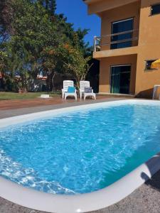 uma piscina com duas cadeiras e uma casa em Pousada Mirante de Areia-Itaúnas em Itaúnas
