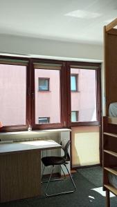 um quarto com 2 janelas, uma secretária e uma cadeira em For rest Hostel em Lublin