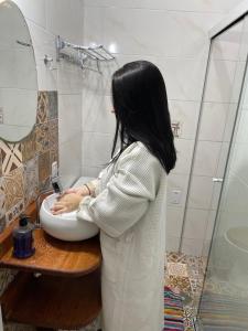a woman washing her hands in a sink in a bathroom at Gara Hospedaria 1 in Imbituba
