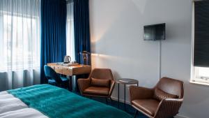 um quarto de hotel com uma cama e duas cadeiras e um lavatório em De Watersport Heeg em Heeg