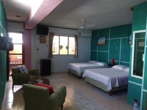 a bedroom with two beds and a couch and a chair at Casa Roja Áabilo'ob in Progreso