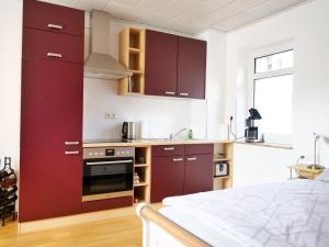 a kitchen with burgundy cabinets and a stove top oven at PfalzZeit in Weisenheim am Berg