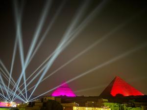 a view of the pyramids at night with red lights at Pyramids top success result in Cairo