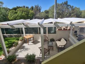 un patio con ombrelloni bianchi, tavolo e sedie di Appartamento La Pergola a Cala Liberotto