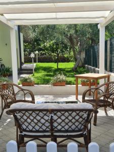 un patio con tavolo, sedie e tavolo di Appartamento La Pergola a Cala Liberotto
