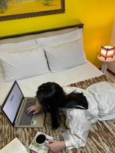 a woman laying on a bed with a laptop at Studio Imbé in Imbituba