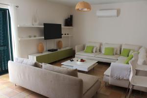 a living room with couches and a flat screen tv at Casa Estelliane in Paderne