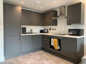 una cucina con armadi grigi e forno a microonde di Cosy Studio Flat - Near City Centre a Doncaster