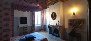 a bedroom with a bed and a fireplace and a window at La Chanoinesse in Salles-Arbuissonnas