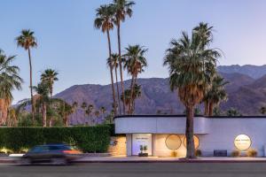 une voiture passant devant un bâtiment avec des palmiers dans l'établissement The Palm Springs Hotel, à Palm Springs