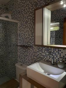 a bathroom with a sink and a toilet and a mirror at Studio Baleia Franca in Imbituba +8 photos