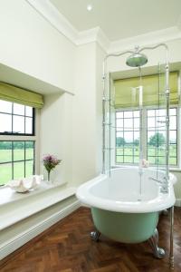 a white bathroom with a tub and windows at Llangoed Hall in Bronllys