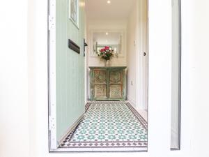 a hallway with a green door and a table with flowers at Bluebell Cottage in Tavistock
