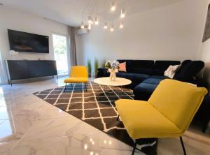 a living room with yellow chairs and a blue couch at Villa Olive Hill in Dobra Voda