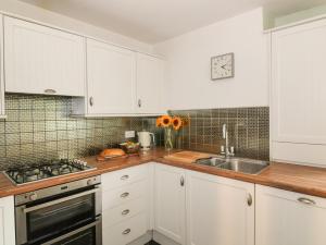 a kitchen with white cabinets and a sink at Greystones Cottage in Crieff