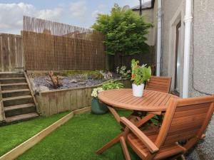 a wooden table and a chair on a small patio at Greystones Cottage in Crieff