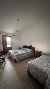 una camera d'albergo con due letti e una finestra di Agriturismo da Lino AGRIPIZZA a Samughèo