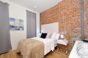 Un dormitorio con una pared de ladrillo y una cama en Steps to Times Square Magnificent 2BR Apartment, en Nueva York