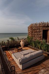a bed sitting on top of a wooden deck with the beach at Nomade Holbox in Holbox Island