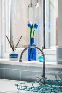 a kitchen sink with a faucet with blue flowers in a window at Aloha Sands in Camber