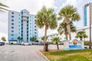 a parking lot with palm trees in front of a hotel at Tropic Isl 501 in Gulf Shores