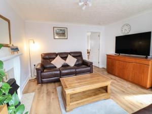 a living room with a leather couch and a coffee table at 24 Via Devana in Swadlincote