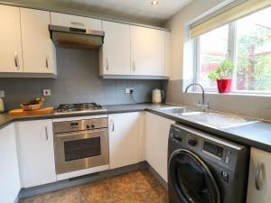 a kitchen with white cabinets and a washer at 24 Via Devana in Swadlincote