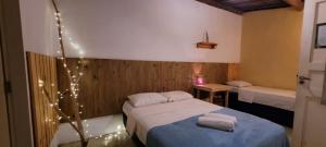 a bedroom with two beds with lights on the wall at Tropicália Hostel e Pousada in Itacaré
