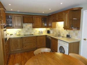 a kitchen with wooden cabinets and a wooden table at Centre Chipping Campden - 3 Bedroom Cottage for 5 in Chipping Campden
