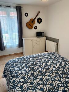 Un dormitorio con una cama y una guitarra en la pared en Maison calme et confortable, 