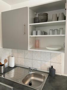 kuchnia ze zlewem i białymi szafkami w obiekcie Maison calme et confortable 