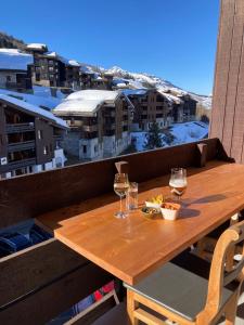 a wooden table on a balcony with glasses of wine at Ruim en modern appartement super centraal gelegen aan de piste in Valmorel