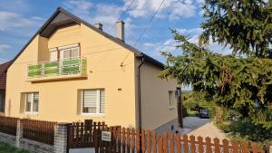 a yellow house with a fence in front of it at Inna Apartman in Hévíz +4 photos