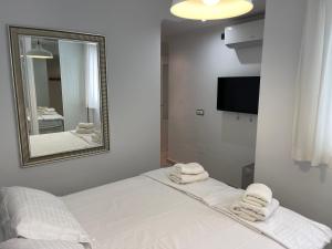 a white bedroom with two towels on a bed and a mirror at La Cala Holiday Retreat in La Cala de Mijas