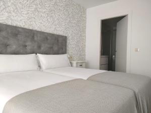 1 dormitorio con 2 camas blancas y cabecero grande en Second Home Arzúa apartamentos, en Arzúa